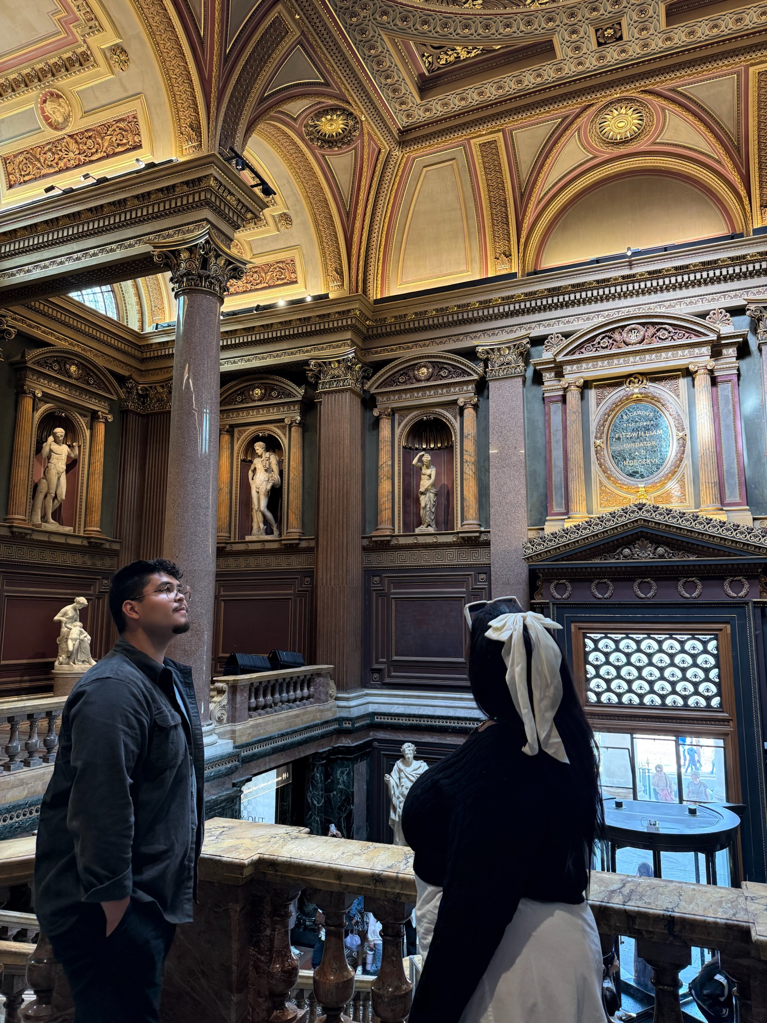 Oscar standing in a building at Cambridge looking at the paintings and dark wood interior