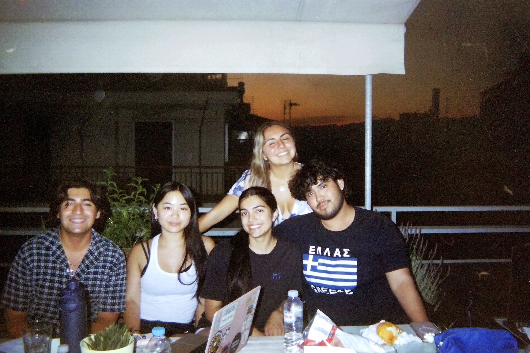 Regina sitting around a table with friends while eating dinner