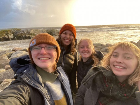 Claire taking a selfie with a group of friends near the chilly waters of the United Kingdom