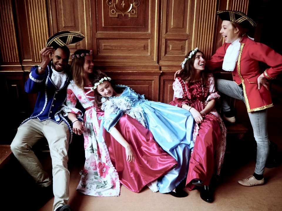 Students in 18th century dress in castle. 