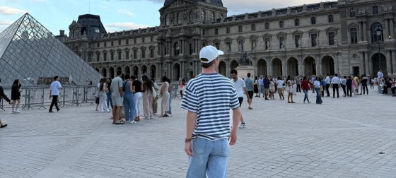 Wesley standing near the Louvre looking away from the camera