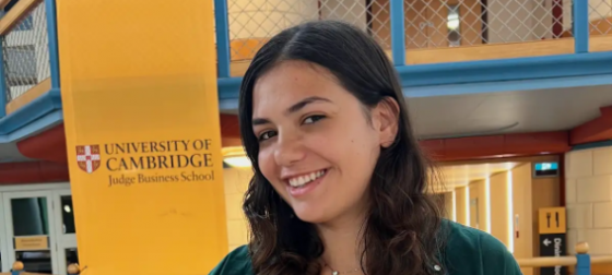 Shiri Gil smiling at the camera in a campus building of the University of Cambridge