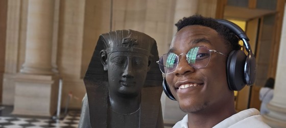 Melnick standing in from of an Eqyptian statue in a museum