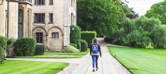 Woman walking on a stone walkway through King's College Cambridge