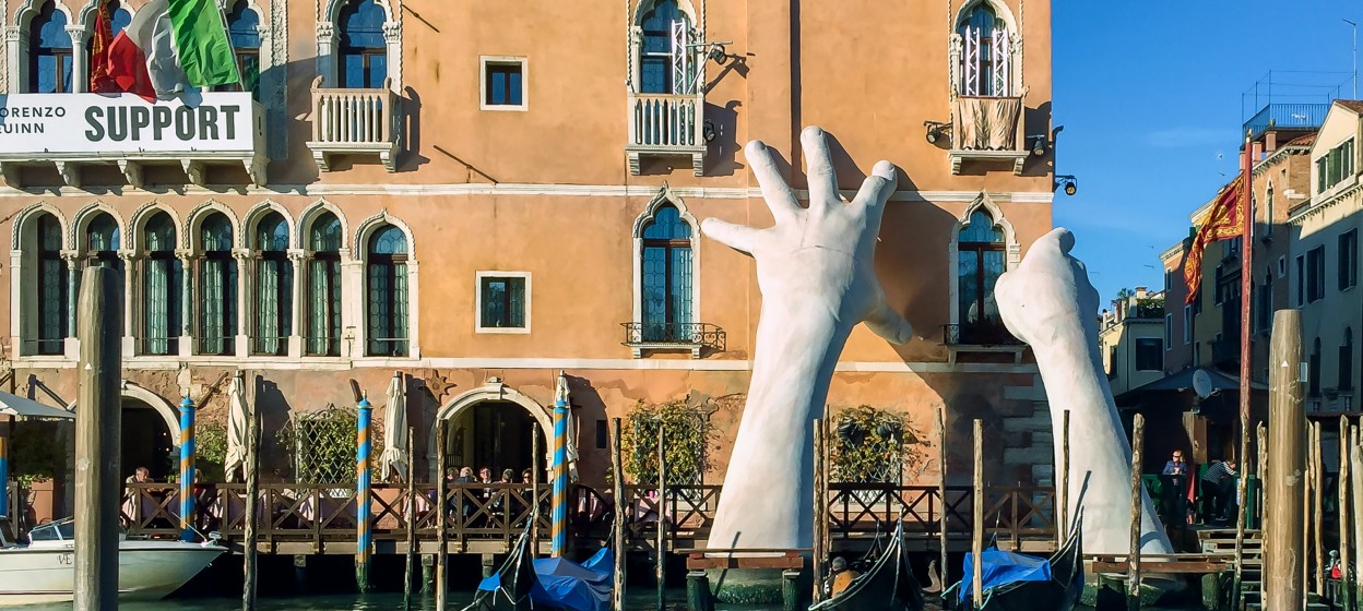 Sculpture of hands supporting a building on the grand canal in Venice, Italy