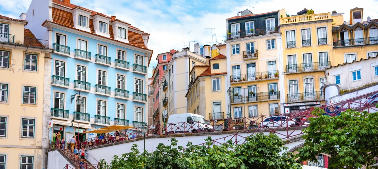 People walking on a street near colorful buildings in Lisbon during the daytime