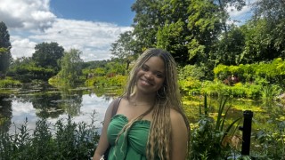 Brooklynne smiling and standing in front of a green garden