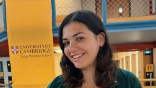 Shiri Gil smiling at the camera in a campus building of the University of Cambridge