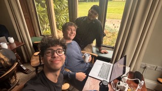 Notavious taking selfie with a couple of friends while they work on research at Cambridge