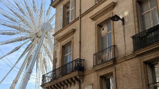 A ferris wheel behind a stone building