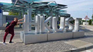 A student pretending to push a large sign that says HKUST