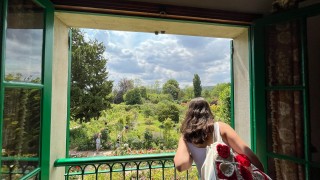 A student looking out of a window that shows a green garden