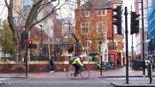A man riding a bike down a street in East London